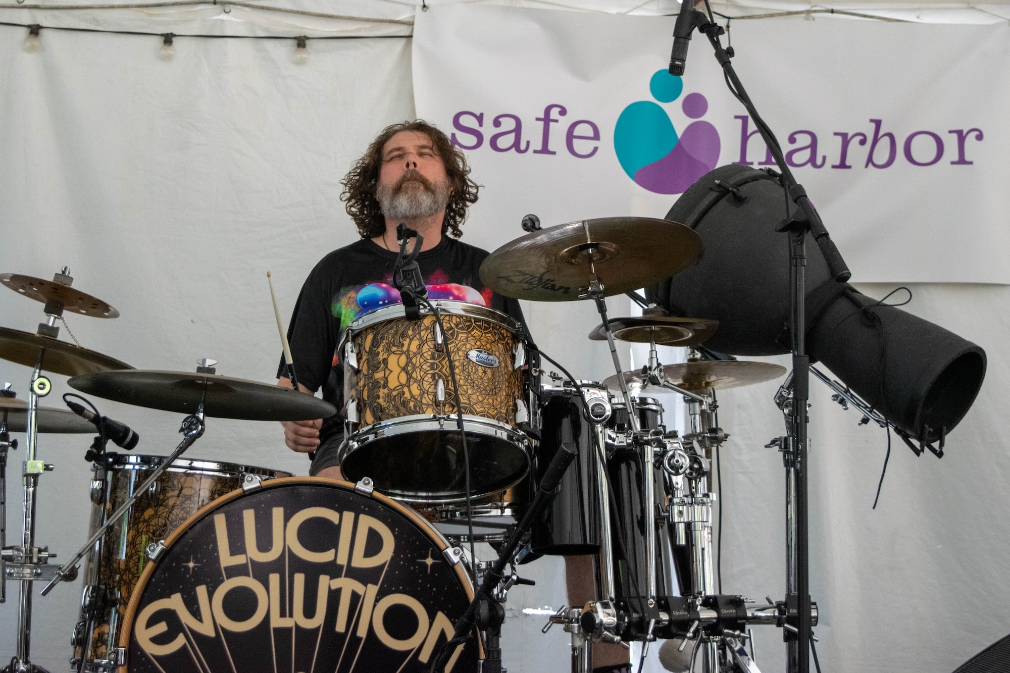 RVA Taco Festival 2026 - Band named Lucid Evolution performing, drummer getting into the music, Safe Harbor banner in background