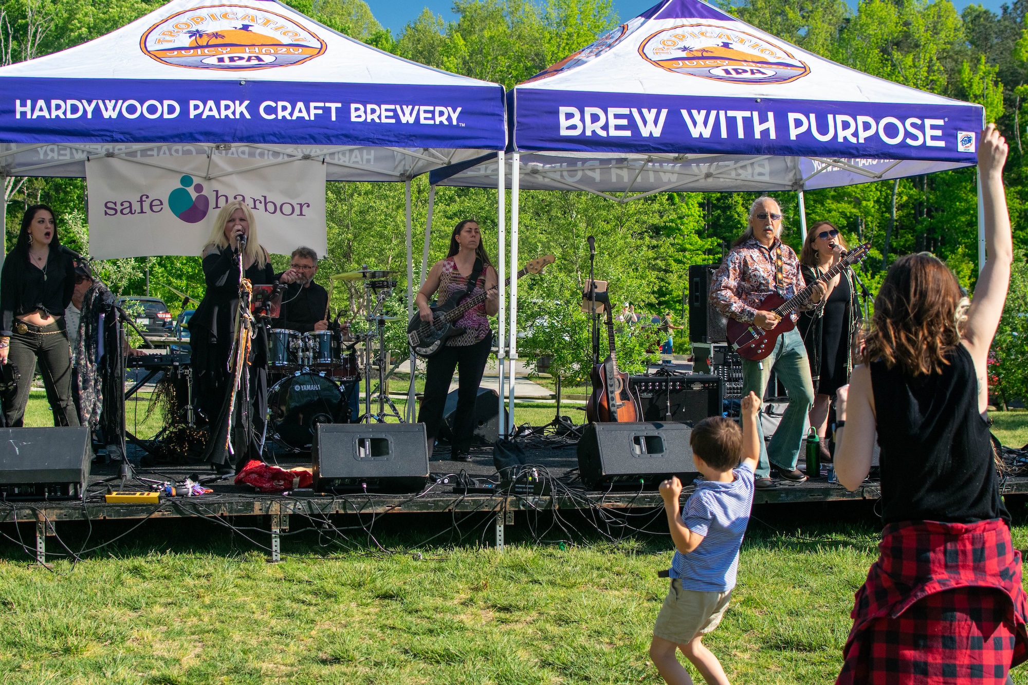 RVA Taco Festival 2026 - Band performing on stage in front of a Safe Harbor banner, with a young boy dancing in the foreground